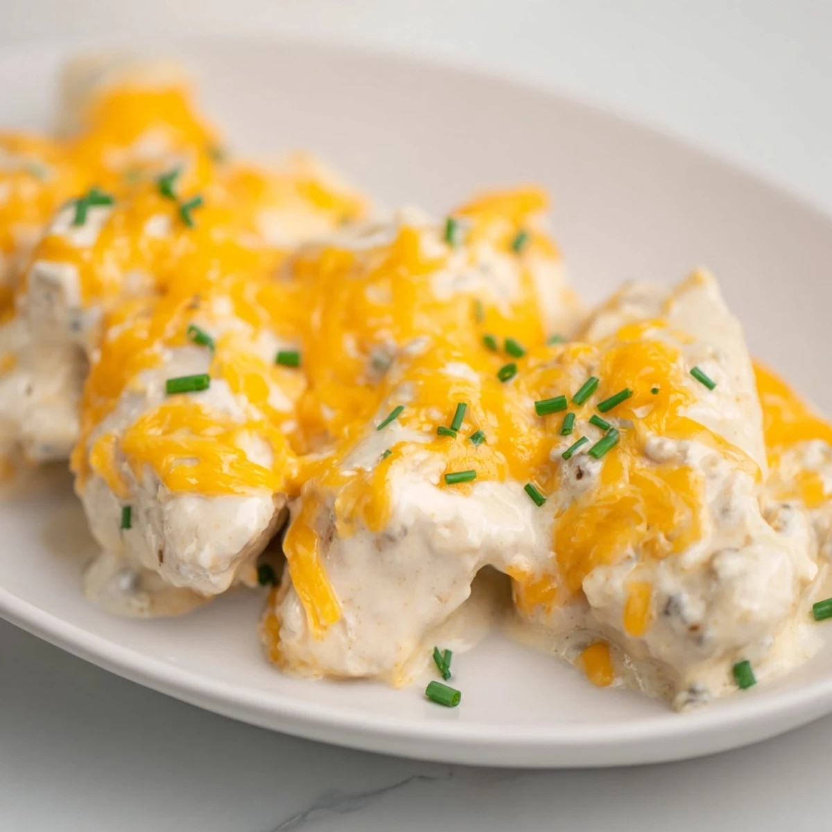 A golden-brown Cheddar Ranch Chicken Bake topped with bubbly cheese, ready to serve with sides.