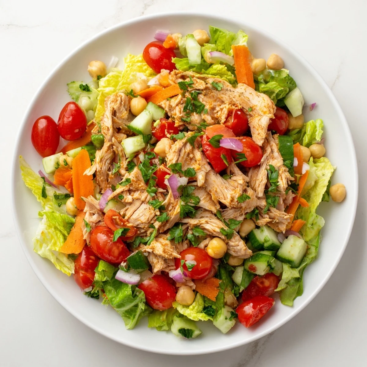 A large bowl overflowing with flavorful chicken salad, tossed with vibrant, fresh ingredients.
