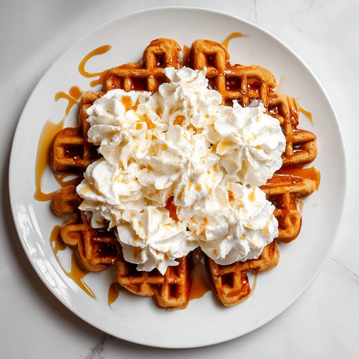 A stack of fluffy gingerbread waffles with whipped cream, perfect for a cozy holiday breakfast.