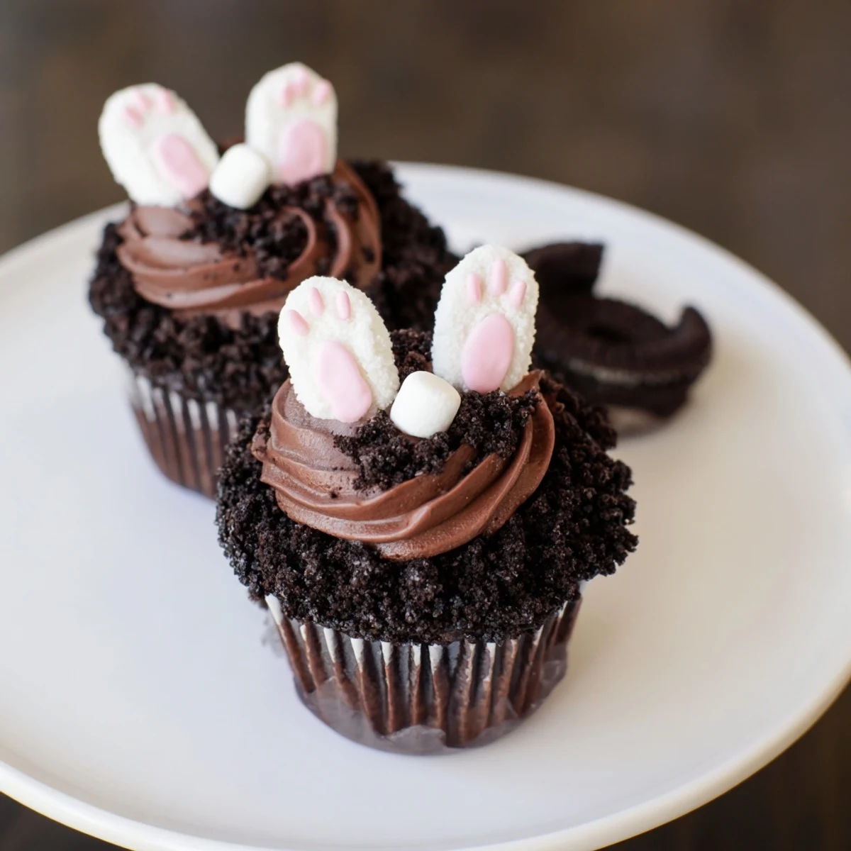 Playful Bunny Burrow cupcakes feature fondant bunny feet peeking from cookie "soil" around the cake.