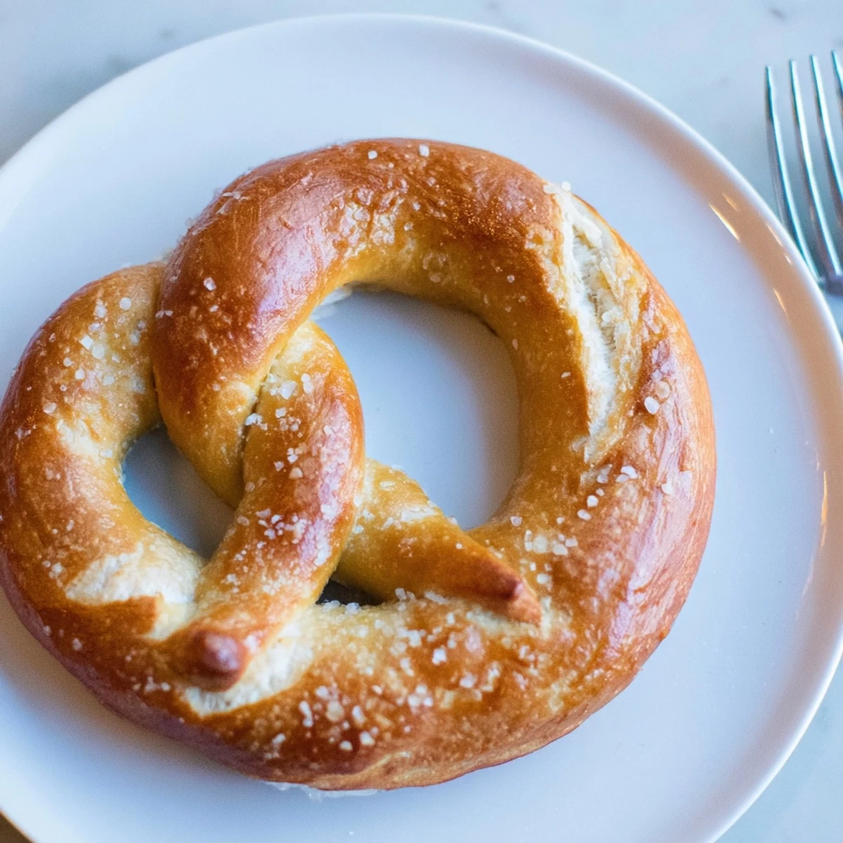 Golden-brown Bretzels Anneau de Fête, shaped into festive rings, are being generously salted.