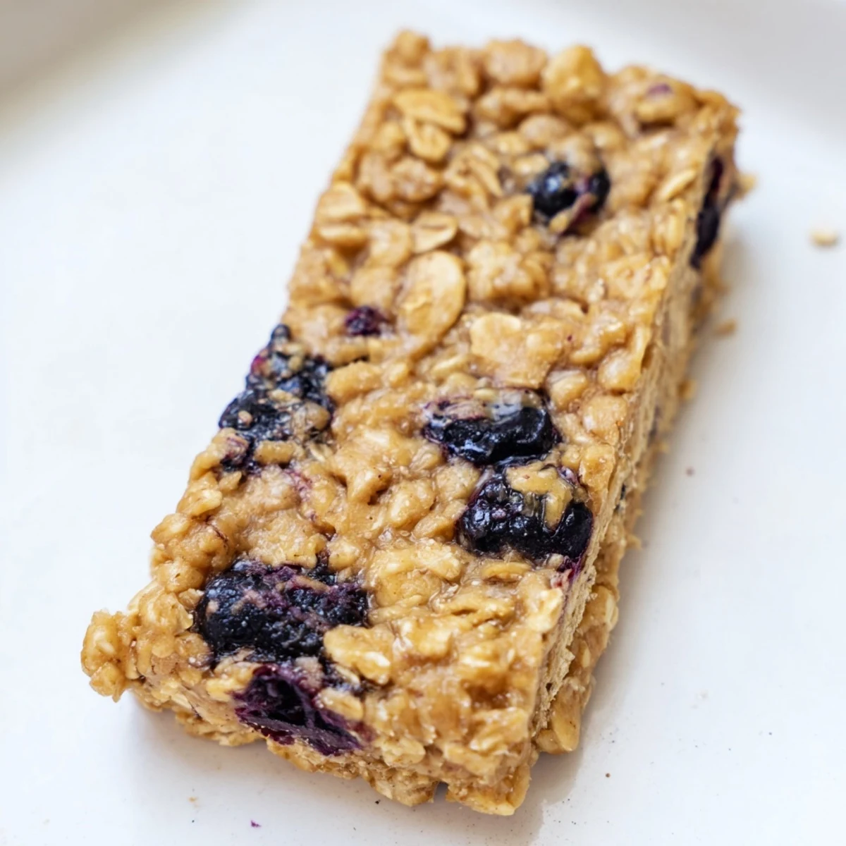 A close-up view of a Blueberry Banana Oatmeal Protein Bar with scattered blueberries, moist and delicious.