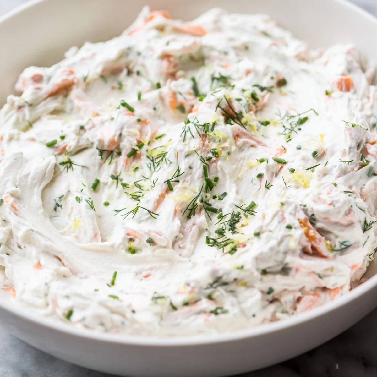 A close-up of creamy Smoked Salmon Dip in a rustic bowl, garnished with fresh dill and lemon wedges for a zesty appetizer.