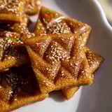 Close-up of crispy, diamond-shaped Tunisian Makroudh cookies, ready to be enjoyed with mint tea.