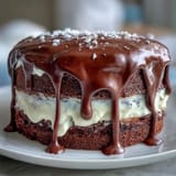 Elegant white chocolate drip graduation cake topped with shimmering gold balloon decorations, ideal for a festive dessert table centerpiece.