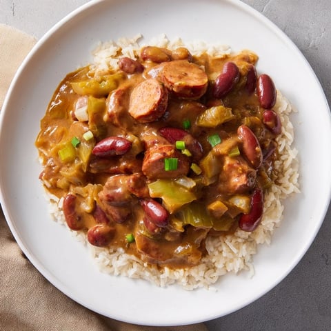 Steaming bowl of Red Beans & Rice, a Creole classic with chunks of sausage and flavorful broth.