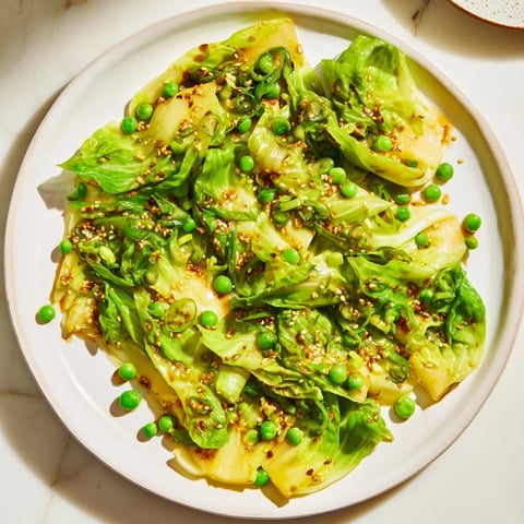 Steaming cabbage stir-fry with garlic and peas, glistening with savory sauce, and ready to enjoy.