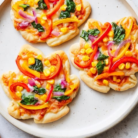Vibrant Fall Foliage Maple Leaf Mini Pizzas, ready to eat, with melted cheese and colorful bell pepper toppings.