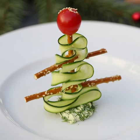 Fresh spiral cucumber ribbon Christmas trees appetizer with vibrant red cherry tomatoes.