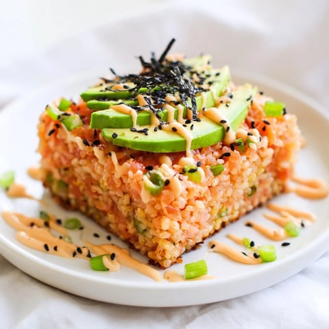 Golden-brown crispy rice salmon stack topped with creamy avocado and spicy mayo, perfect appetizer.