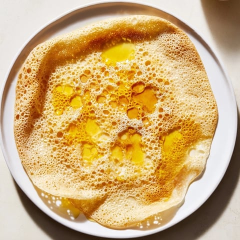 Golden, bubbly Moroccan Baghrir crepes are porous, perfect for soaking up sweet honey-butter.