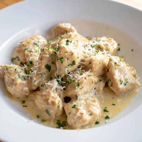 Golden-brown Creamy Garlic Chicken Bites resting in a glossy, rich garlic cream sauce, garnished with fresh parsley.