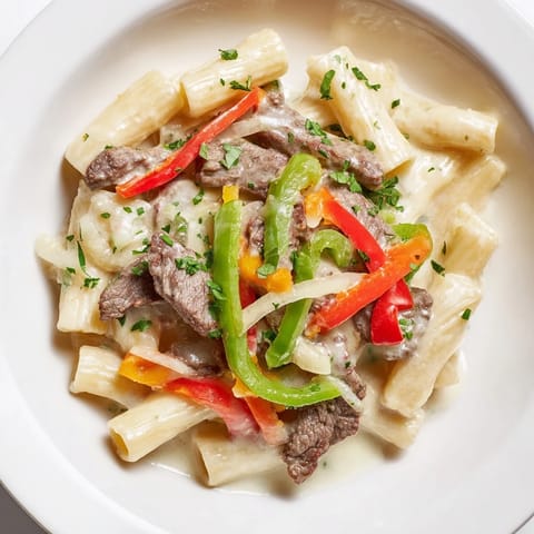 This warm Philly Cheesesteak Pasta features savory steak, bell peppers, and a rich, cheesy sauce.