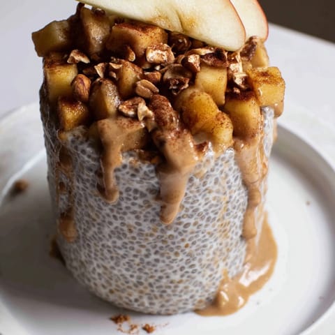 A beautiful serving of Apple-Chia Pudding, topped with peanut pieces and featuring peanut butter swirls.