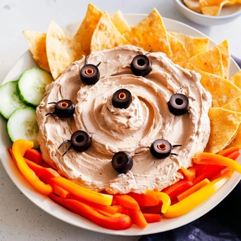 Creepy Crawly Spiderweb Platter: A spooky Halloween appetizer, featuring a creamy dip spiderweb and crunchy veggies.