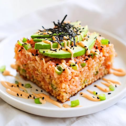 Golden-brown crispy rice salmon stack topped with creamy avocado and spicy mayo, perfect appetizer.