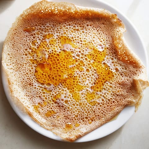Warm, freshly made Moroccan Baghrir pancakes, ready to be drizzled with flavorful butter and honey.