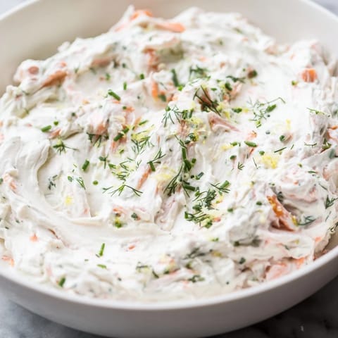 A close-up of creamy Smoked Salmon Dip in a rustic bowl, garnished with fresh dill and lemon wedges for a zesty appetizer.