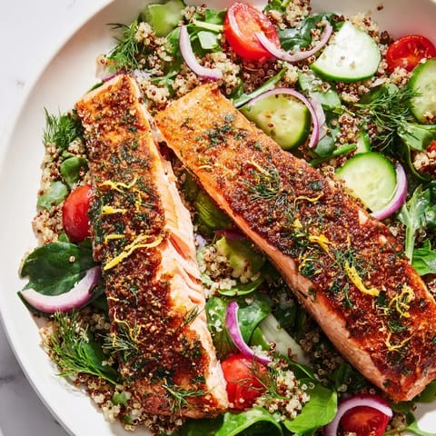 A vibrant Lemon Herb Salmon Salad with fluffy quinoa, crisp greens, cucumber, and red onion tossed in citrus dressing.