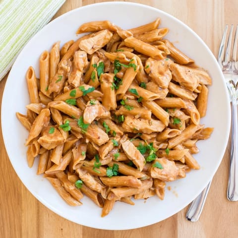 A close-up of Honey Chipotle Chicken Pasta showing creamy sauce coating al dente penne and melted Parmesan.  