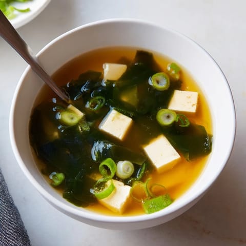 Japanese wakame soup with soft tofu cubes, vibrant scallions, and a clear dashi broth.  