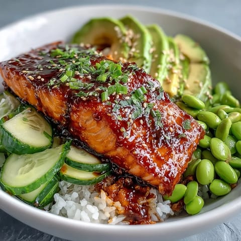 Honey Sriracha Salmon Bowl with glazed fillet, fluffy jasmine rice, crisp cucumber, and creamy avocado topped with spicy mayo.
