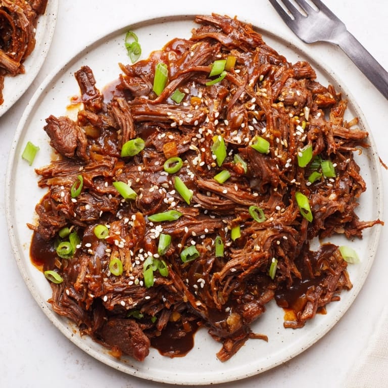 Savory Slow Cooker Honey Garlic Beef: Rich, dark sauce coats fork-tender shredded beef.
