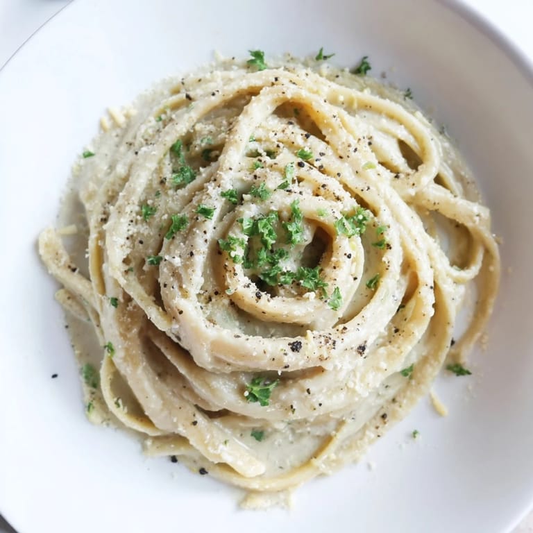 A steaming bowl of Skinny Alfredo Garlic Parmesan Snowy Pasta with a rich, garlicky, creamy sauce.