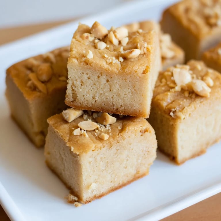 Perfectly baked peanut butter mochi cake with a delightful, slightly crispy top, enjoyed with a cup of tea.