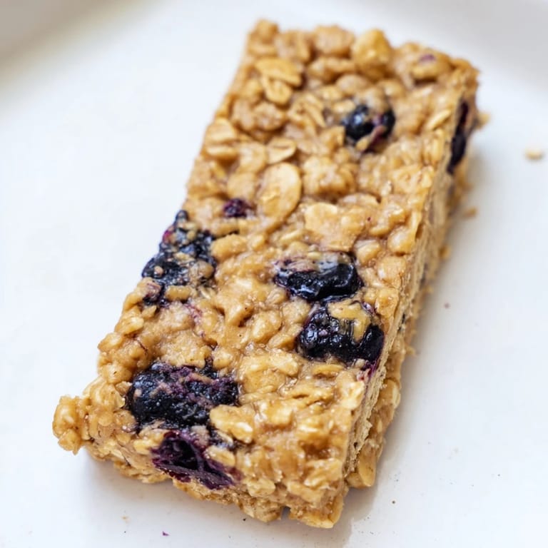 A close-up view of a Blueberry Banana Oatmeal Protein Bar with scattered blueberries, moist and delicious.