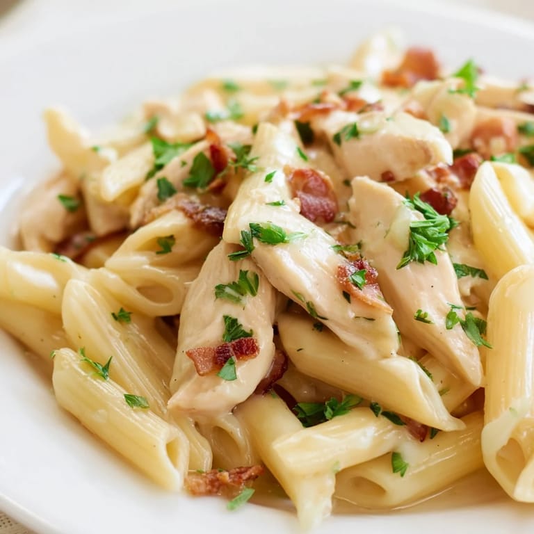Close-up of Creamy Chicken Bacon Penne, steam rising from cheesy sauce, served with crusty bread for a satisfying weeknight dinner.