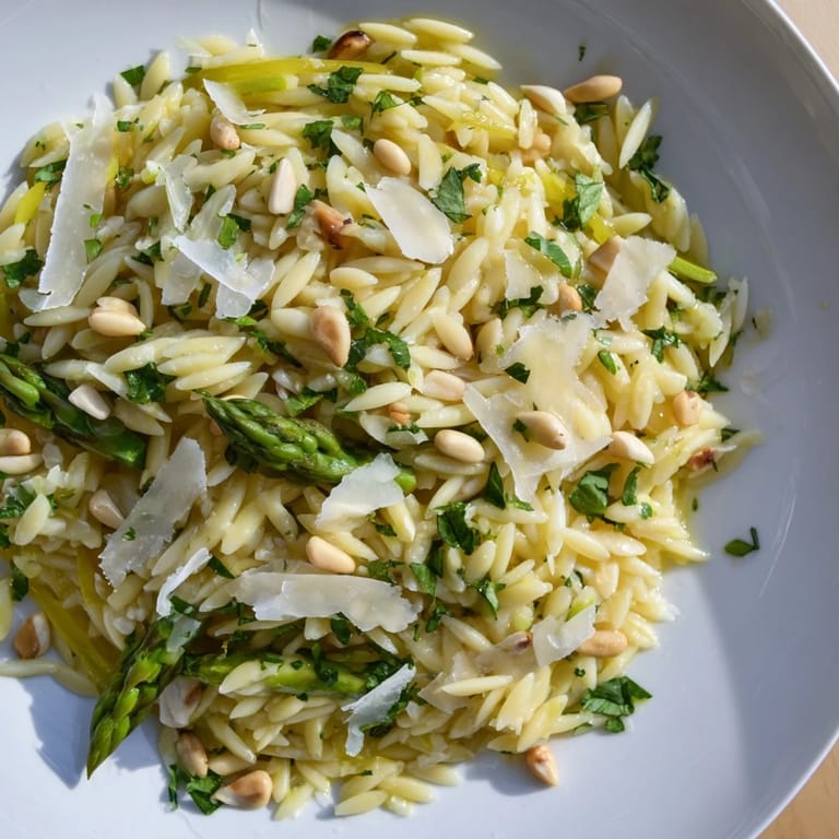 Enjoy a colorful bowl of Asparagus Lemon Orzo Salad, featuring al dente orzo, crisp shaved asparagus, and fresh herbs drizzled in lemon dressing.