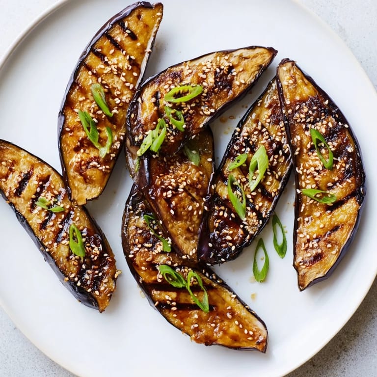 Golden miso glazed eggplant brushed with savory glaze, served warm beside fluffy white rice.