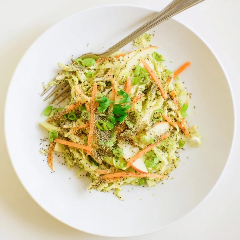 Close-up of Green Cabbage and Apple Slaw, showcasing crunchy texture from shredded cabbage and apples, topped with fresh parsley and poppy seeds for garnish.