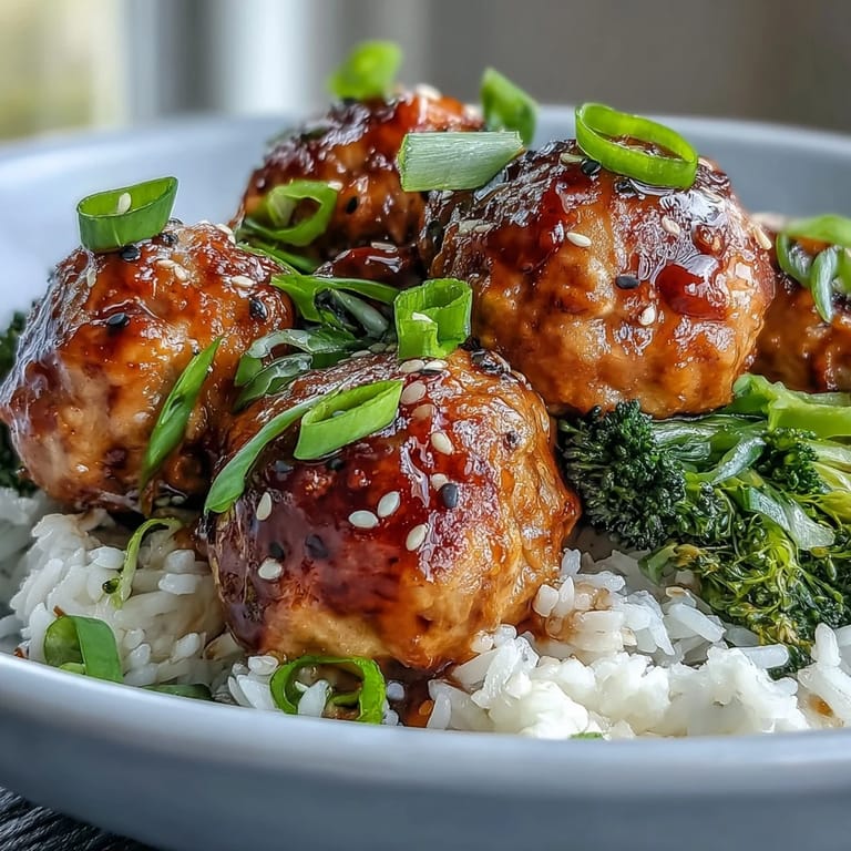 Baked Honey Garlic Turkey Meatballs piled in a bowl, garnished with sesame seeds and fresh green onions.