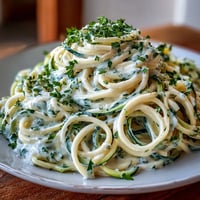 Creamy cottage cheese Alfredo sauce served over tender zucchini noodles, garnished with fresh parsley and Parmesan.  