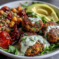 A vibrant Spring Buddha Bowl with roasted vegetables, crispy falafel, and creamy lemon-tahini dressing served over quinoa.  